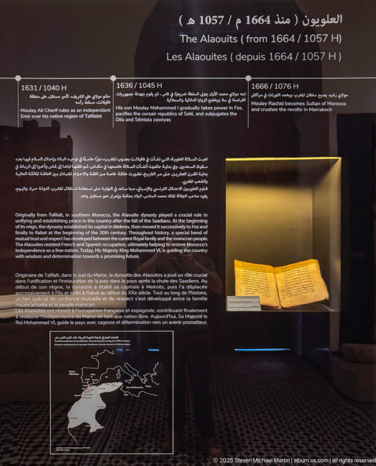 Alaouite dynasty museum panel with bilingual text, map, timeline, and an open book or manuscript in a lit case.