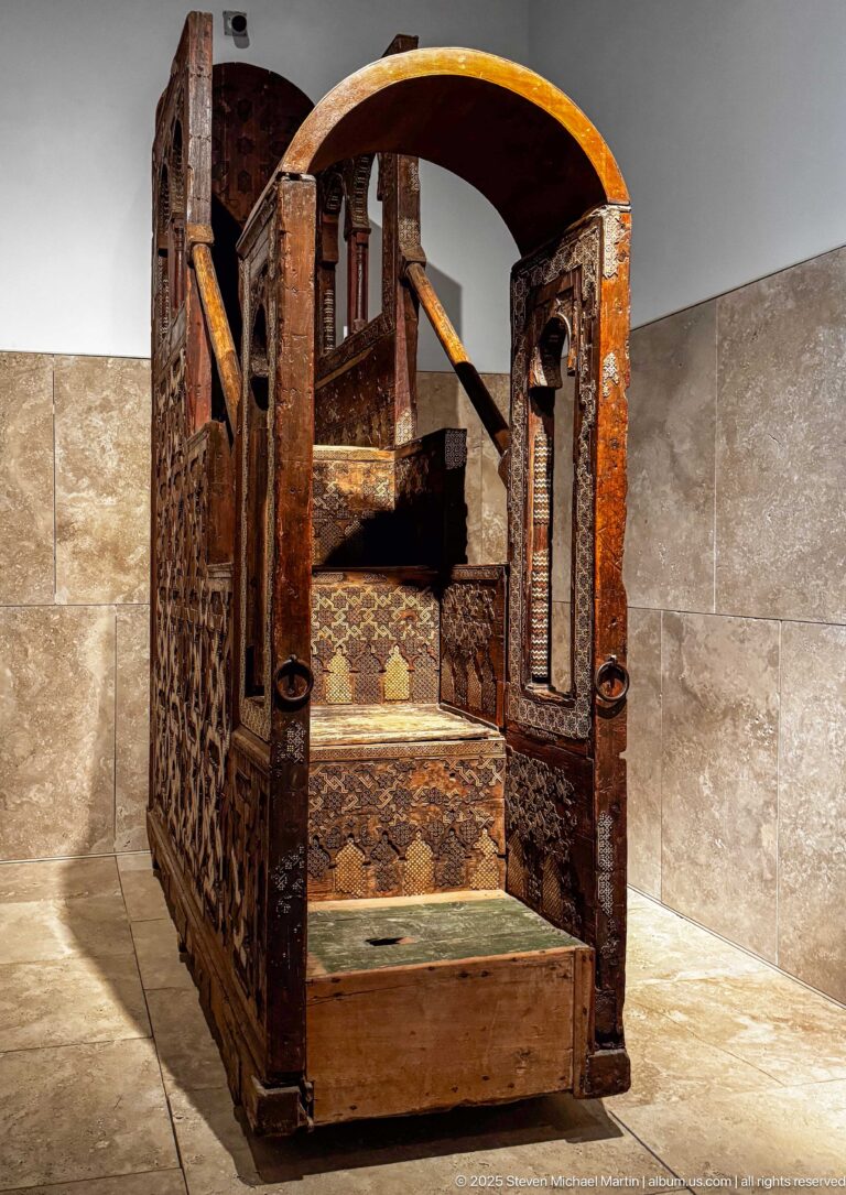 Tenth-century wooden minbar from the Andalusian Mosque in Fes, with steps, arched entrance, pierced panels, and geometric decoration.