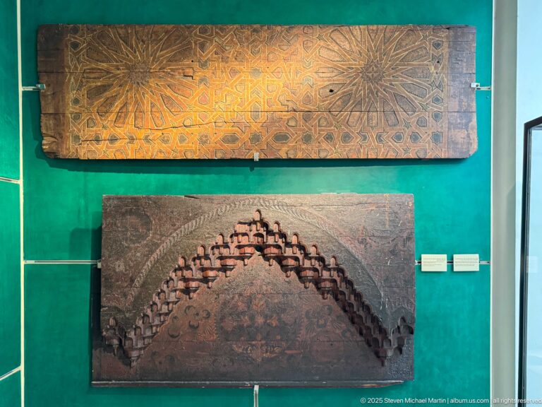 Two mounted wooden architectural panels, one with interlaced star geometry and one with a deep stepped arched relief.