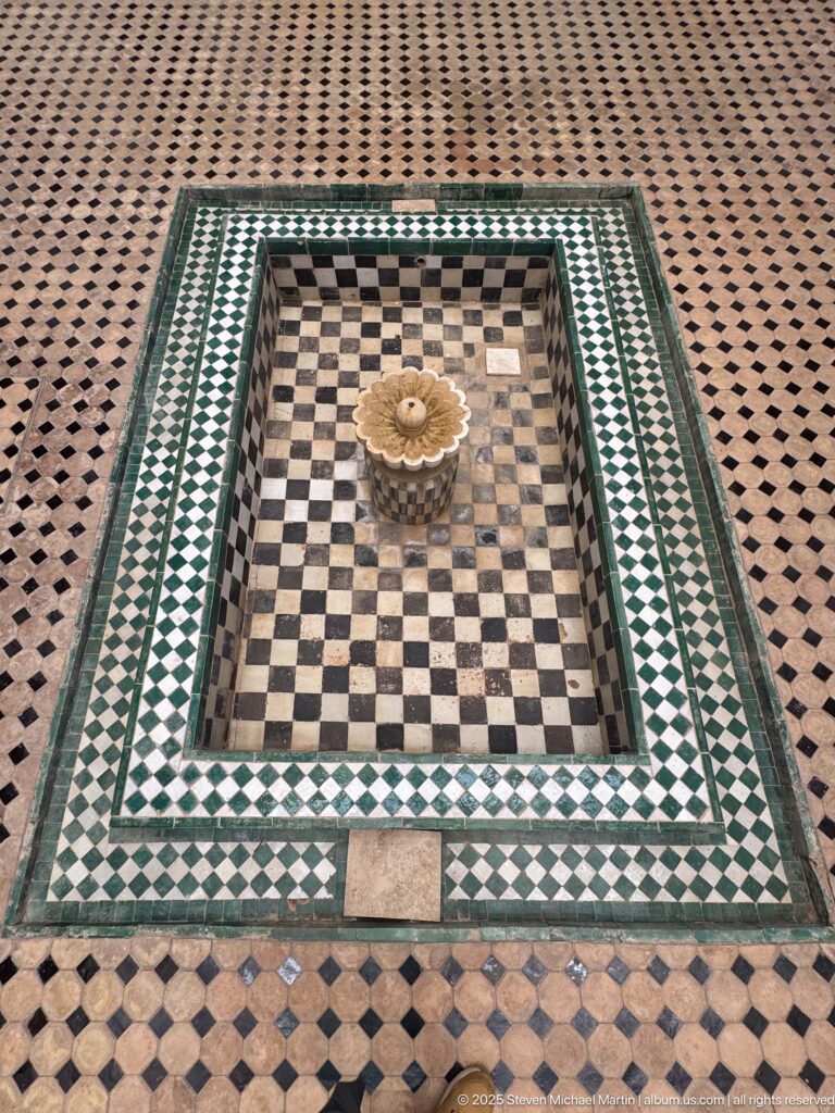 Square sunken tiled basin with black-and-white interior checks, green zellij borders, and a small scalloped center element.