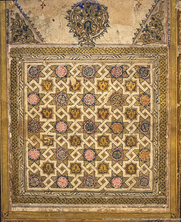 Rectangular polychrome panel of white geometric interlace enclosing small colored motifs, surrounded by a narrow ornamental border.