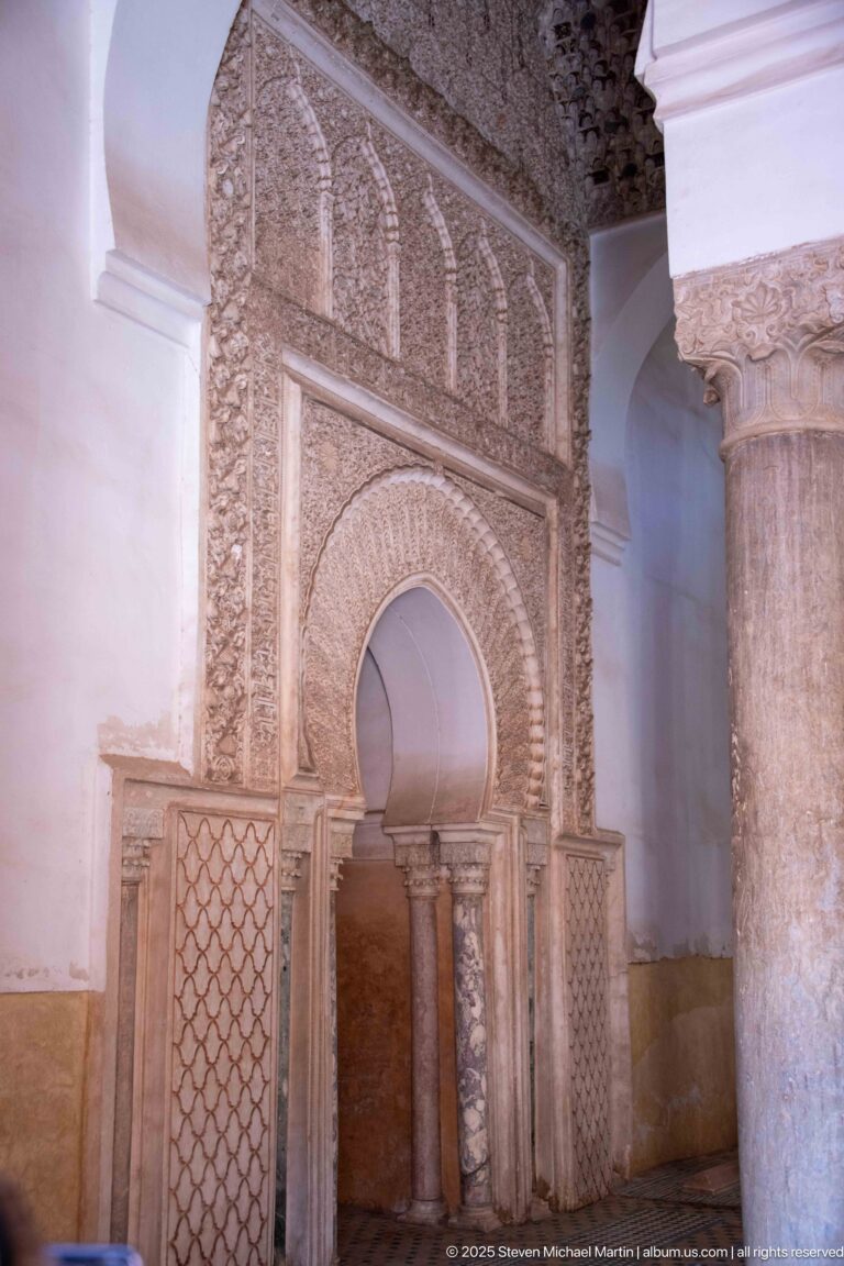 Horseshoe-arched wall niche framed by carved stucco, small columns, and geometric lattice panels.