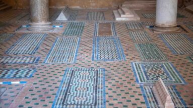 Several patterned zellij grave panels extend across the floor between marble column bases.