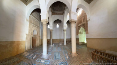 Long view through marble columns over patterned grave panels in the tiled funerary chamber.