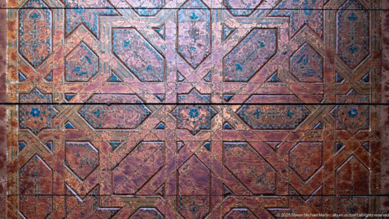 Faded polychrome wooden panel covered with interlocking polygons and small star motifs.