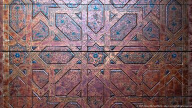 Faded polychrome wooden panel covered with interlocking polygons and small star motifs.