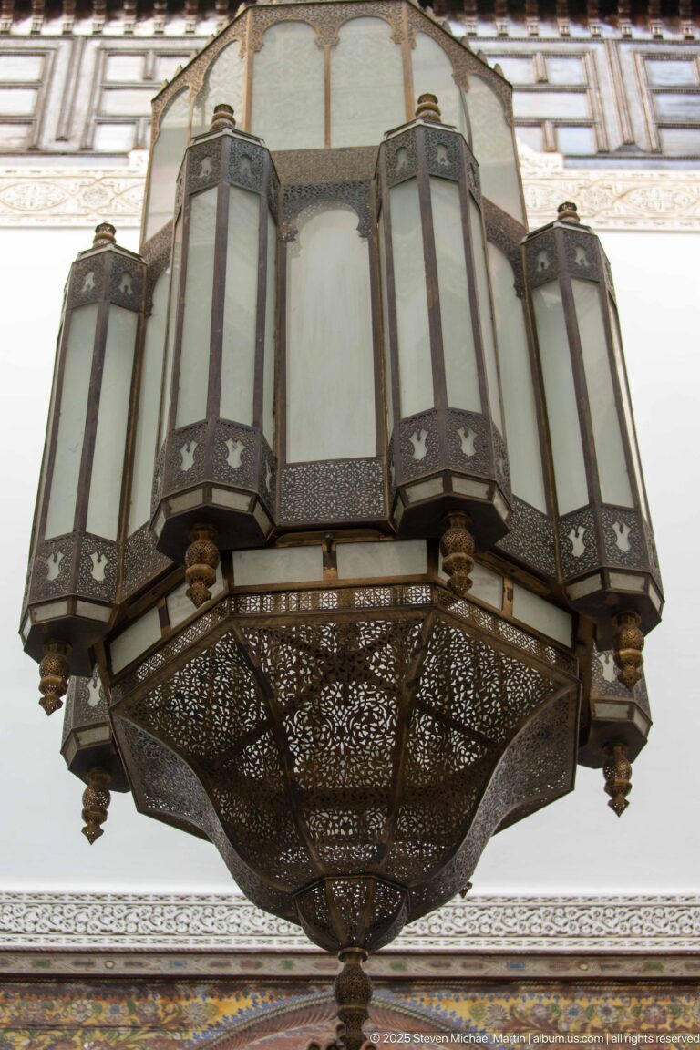 Large faceted hanging lantern with pierced metalwork and translucent panels viewed from below inside Riad Fes Maya.