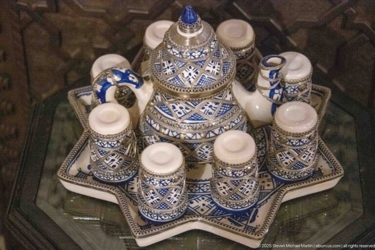 Blue-and-white painted ceramic tea set with lidded central pot and cups arranged on a star-shaped tray.