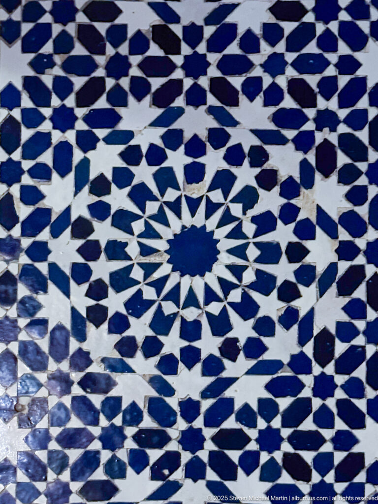 Radial blue-and-white zellij mosaic centered on a star and built from interlocking geometric tile pieces.