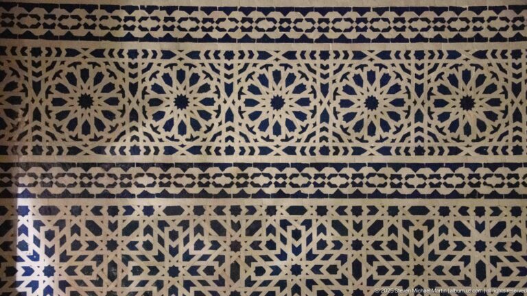 Blue-and-white zellij panel with repeated star rosettes, lattice geometry, and narrow patterned borders.