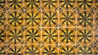 Repeating yellow, black, green, and red floral-patterned ceramic tiles filling the frame.