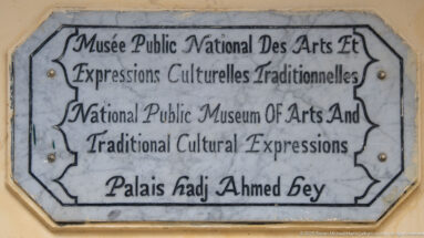 Weathered bilingual plaque identifying the National Public Museum of Arts and Traditional Cultural Expressions at Palais Hadj Ahmed Bey.