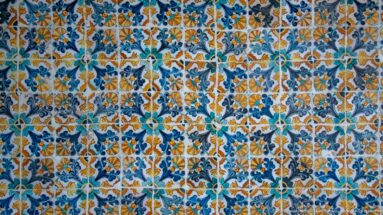 Close view of repeating blue, turquoise, green, ochre, and white floral-patterned ceramic tiles.