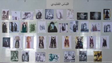 Wall panel about traditional clothing with Arabic heading and rows of historic photographs, portraits, and garment images.
