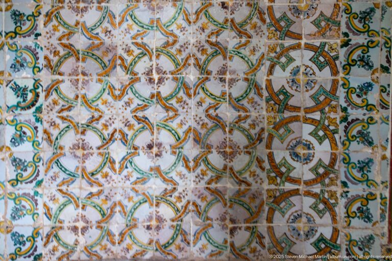 Close view of polychrome palace tiles with interlaced geometric medallions, foliage, flowers, and areas of surface wear.