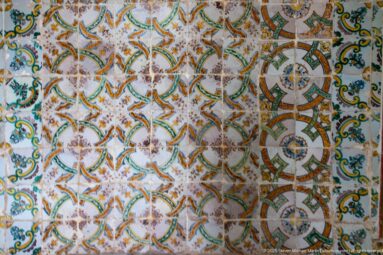 Close view of polychrome palace tiles with interlaced geometric medallions, foliage, flowers, and areas of surface wear.