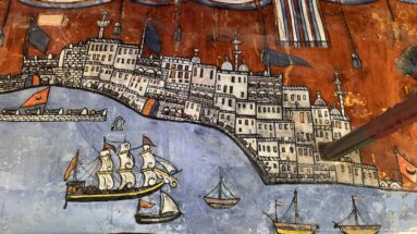Painted harbor scene with walled waterfront city, towers, flags, and several sailing vessels on blue water.