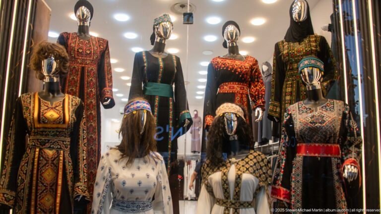 Shop mannequins wearing richly embroidered long garments in red, gold, green, black, and cream.