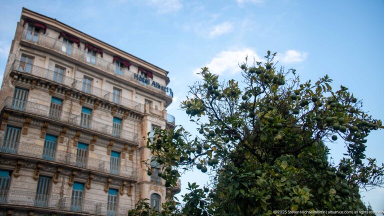 Ornate corner hotel with green shutters, wrought-iron balconies, carved stone details, and a HOTEL ALBERT sign.