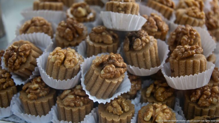 Small fluted pastries in paper cups, each topped with a walnut half.