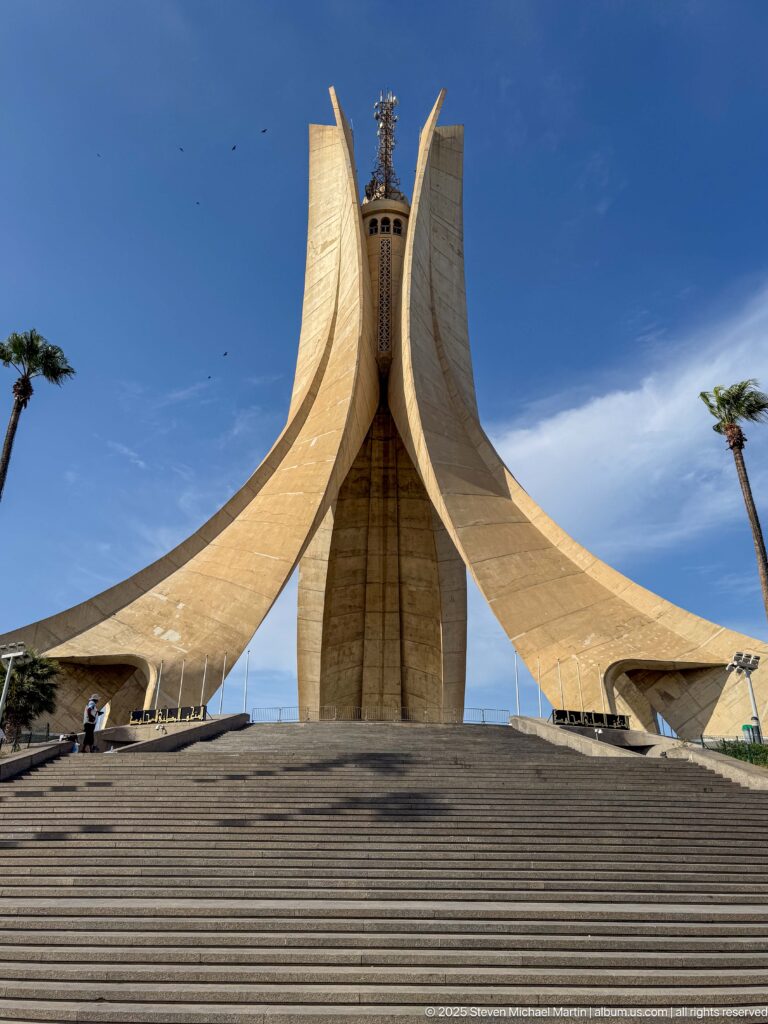 Wide frontal view of the Martyrs’ Memorial above a broad empty staircase under blue sky.