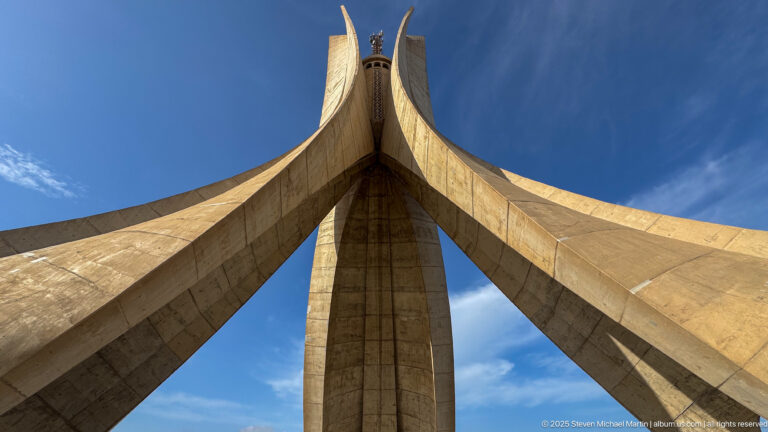 Extreme low-angle view looking upward between the converging concrete fins of the Martyrs’ Memorial.