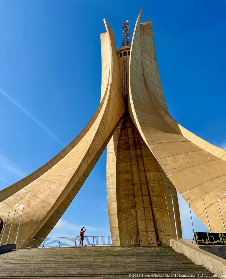 Frontal low-angle view of the Martyrs’ Memorial with broad steps and a small visitor at the base.