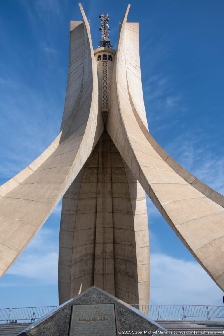 Frontal low-angle view of the three sweeping concrete fins of the Martyrs’ Memorial against blue sky.
