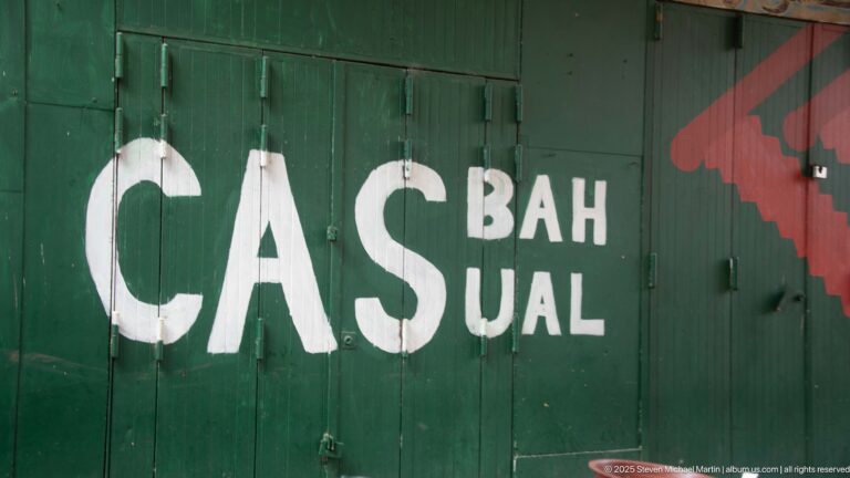 Large white CASBAH lettering painted across dark green metal shutters with smaller letters and a red graphic.