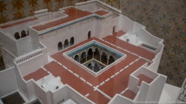 Oblique view of a palace scale model showing white walls, red roof terraces, arcaded openings, and a central courtyard.