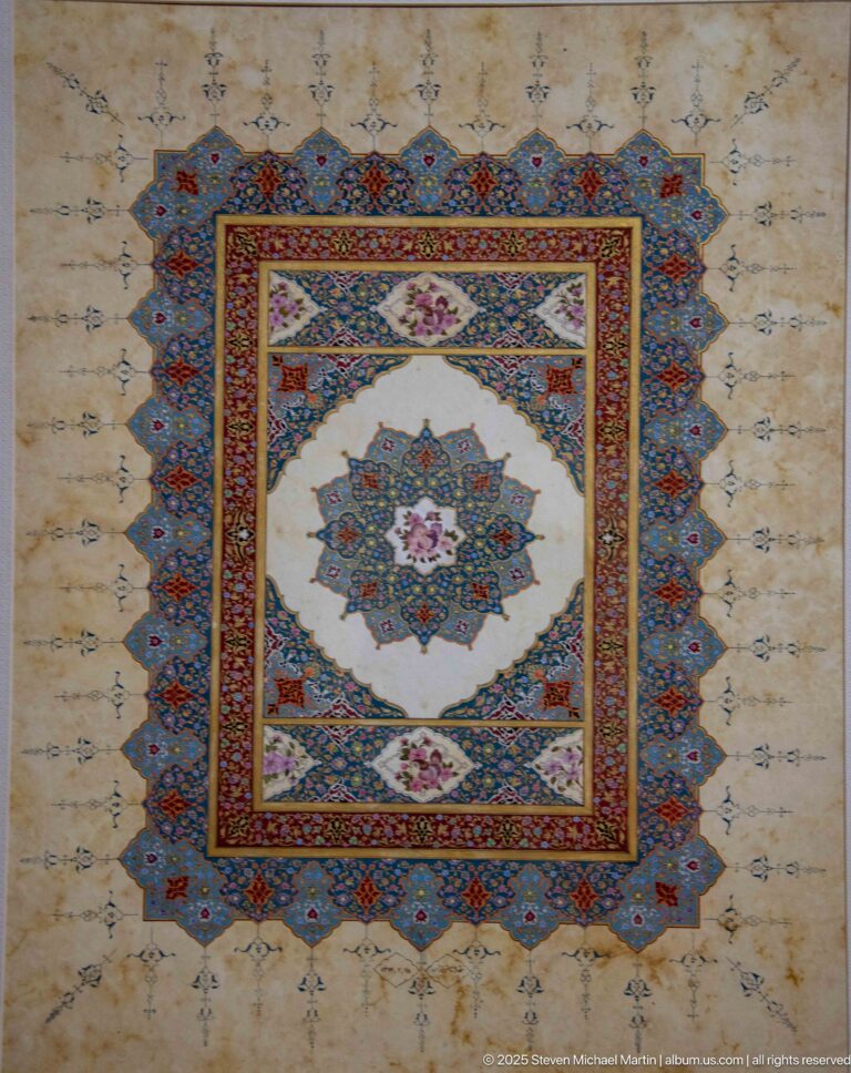 Square illuminated artwork with central blue-and-pink star medallion, nested red and blue geometric borders, and fine floral ornament.