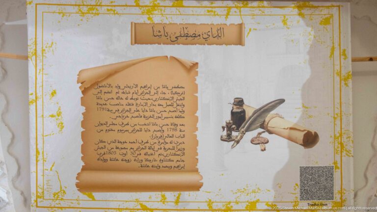 Arabic interpretive panel with parchment-style text beside an illustrated ink vessel, quill, rolled paper, and writing tools.