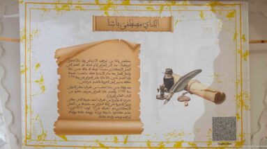 Arabic interpretive panel with parchment-style text beside an illustrated ink vessel, quill, rolled paper, and writing tools.