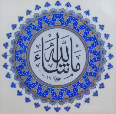 Large black Arabic calligraphy in a pale oval surrounded by dense cobalt-blue and gold floral illumination and small outer motifs.