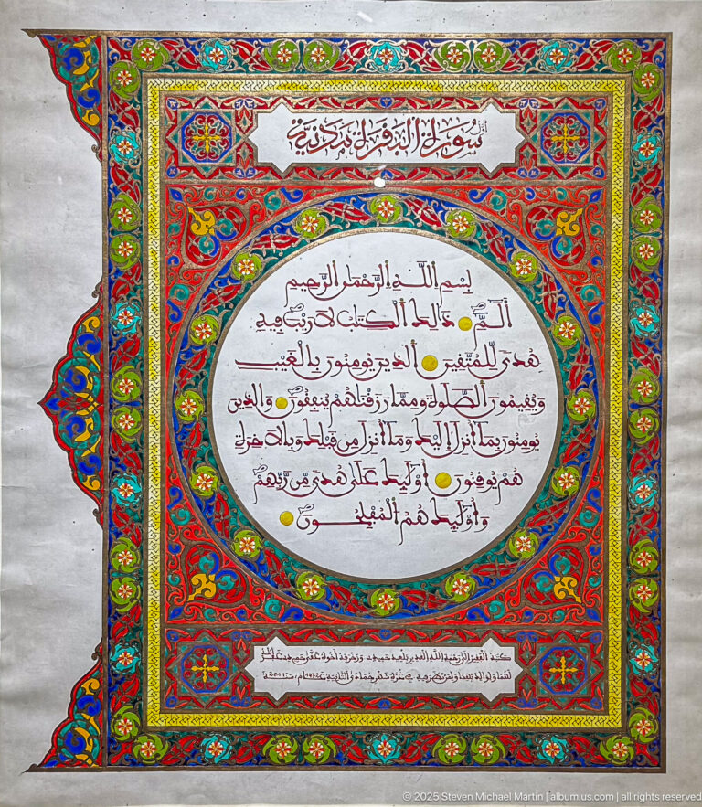 Arabic text in a white oval surrounded by elaborate red, blue, green, and gold illumination, with heading and lower text panels.