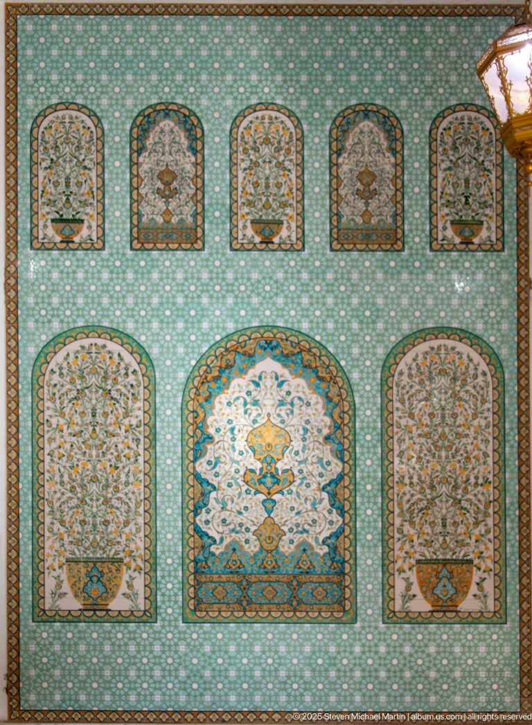 Turquoise and multicolored floral tile panel with arched compartments, scrolling plants, and dense borders.