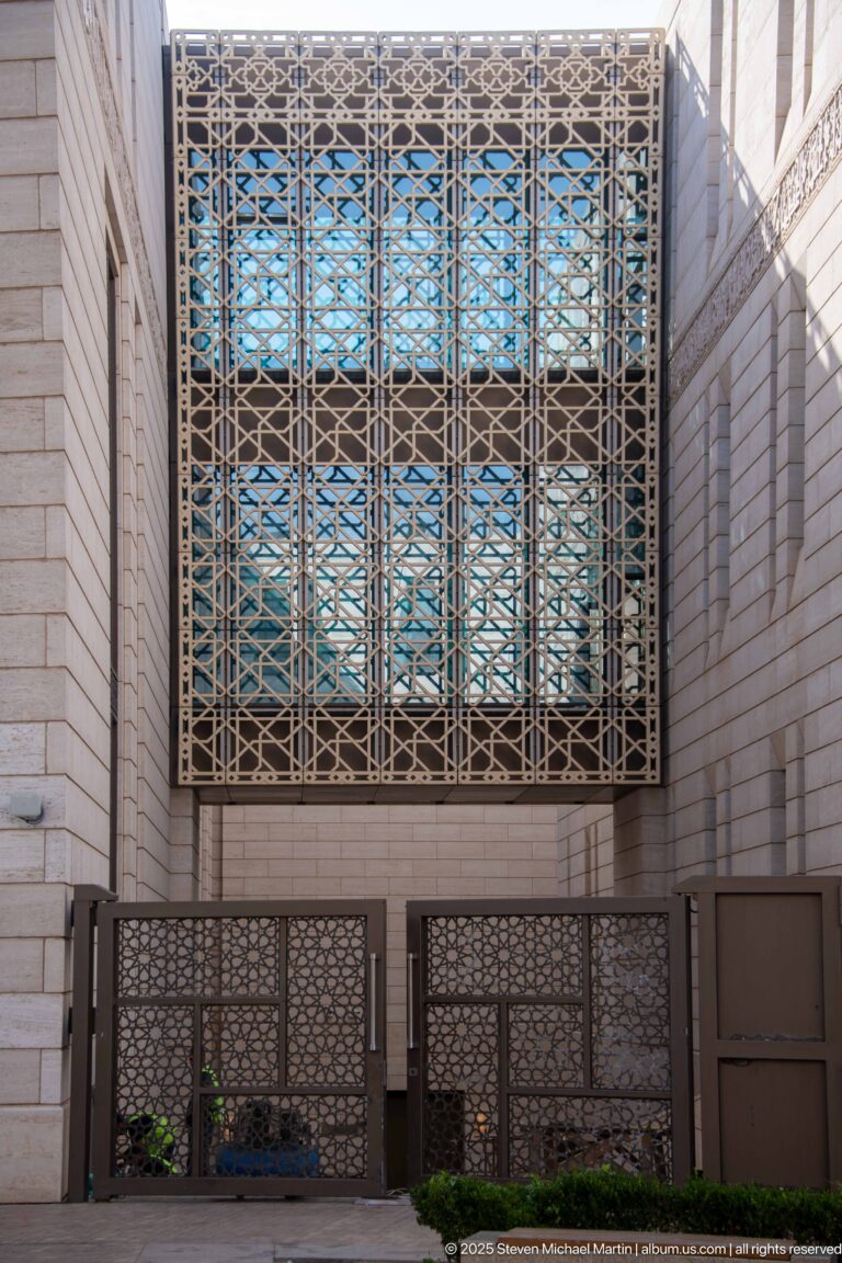 Large geometric metal lattice covering a blue-glazed opening above matching patterned barriers at the Great Mosque of Algiers.