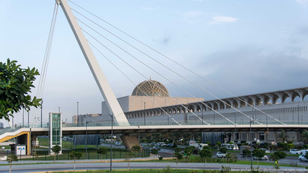 Cable-stayed bridge crosses in front of the mosque’s patterned dome and long arcaded roofline.