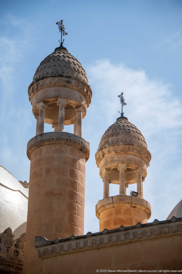 Two small domed turrets with columns and metal finials on the roofline of Notre-Dame d’Afrique.