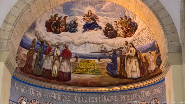 Close view of the Notre-Dame d’Afrique apse mural with the Virgin and Child among clouds and surrounding religious figures.