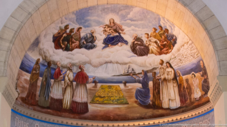 Painted apse mural inside Notre-Dame d’Afrique with multiple religious figures arranged around a central sacred scene.