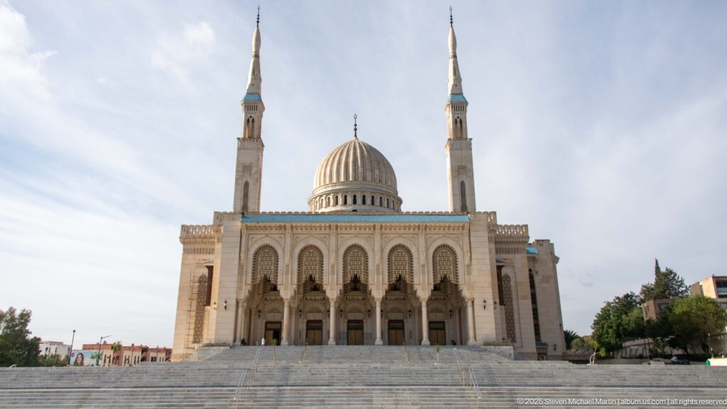 Centered full view of Amir Abdel Kader Mosque with broad steps, arched façade, central dome, and twin minarets.