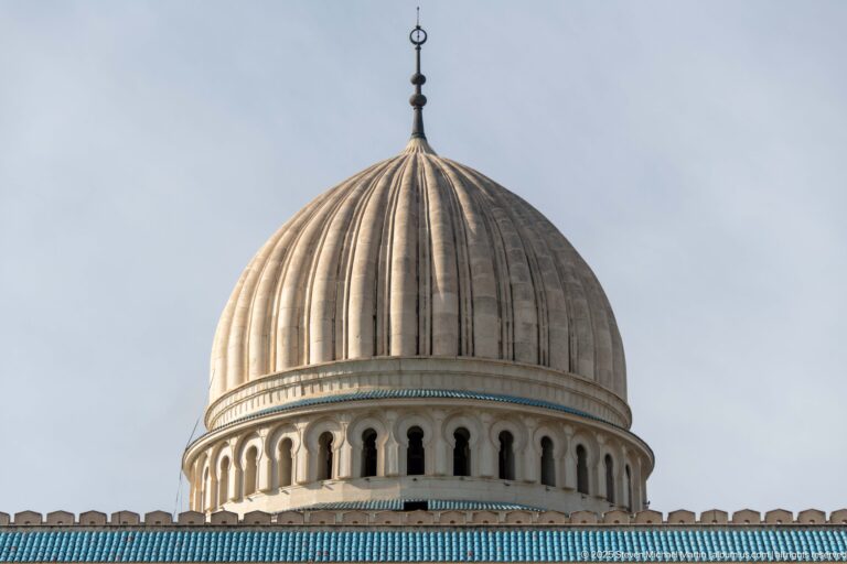 Close view of the mosque’s ribbed central dome, finial, arched drum openings, and turquoise-blue tile band.