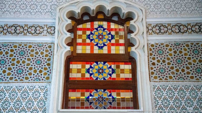 Narrow stained-glass panel with three stacked blue-centered star medallions in red, yellow, and amber glass.