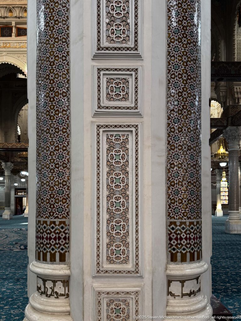 Close view of mosque pier with two mosaic-covered shafts and narrow framed panels of repeating geometric ornament.