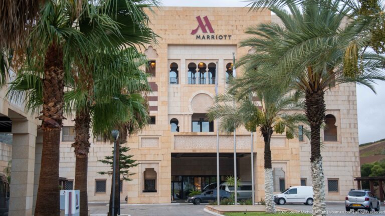 Constantine Marriott façade with stone cladding, arched windows, palm trees, and the Marriott name above the entrance.