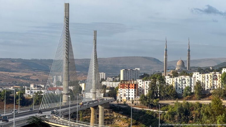 White cable-stayed bridge in Constantine with the twin minarets and dome of the Emir Abdelkader Mosque behind it.