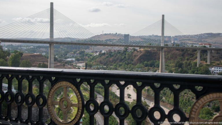 Salah Bey cable-stayed bridge spanning Constantine’s gorge beyond an ornate black metal railing in the foreground.
