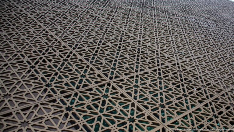 Close view of a pierced geometric screen with interlocking star patterns and turquoise surfaces visible through the lattice.