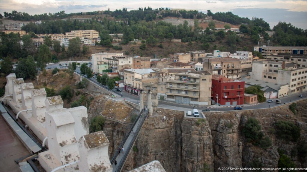 Constantine buildings beside sheer gorge cliffs with a narrow pedestrian bridge crossing the rocky chasm.